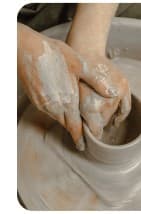 Hands shaping clay on the wheel