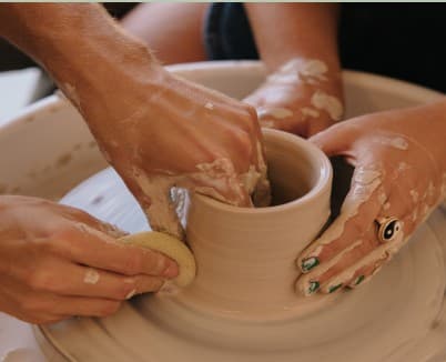 Two people throwing a pot together